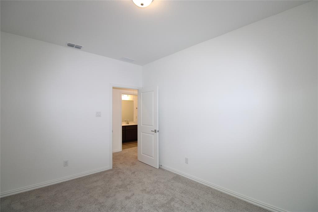 Neutral-toned carpeting, smooth-finish walls, ceiling-mounted lighting, and a solid-core two-panel interior door