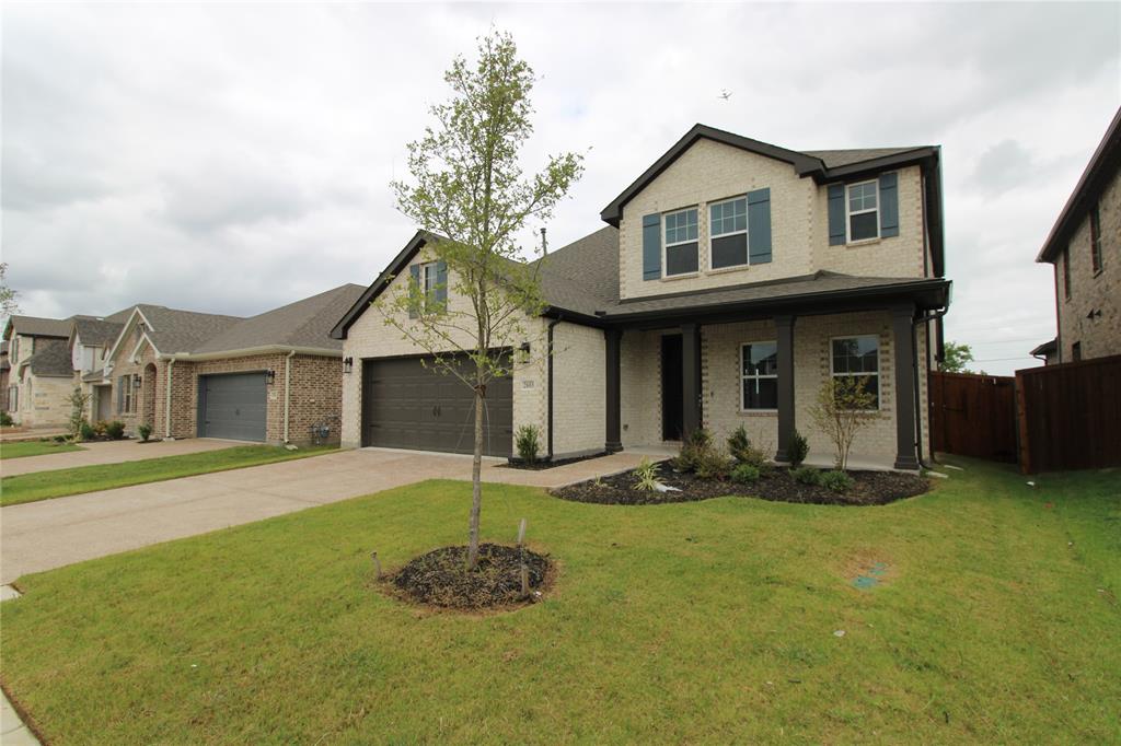 Two-story brick exterior featuring a covered front porch, dark-toned shutters, and a multi-car garage with a concrete driveway
