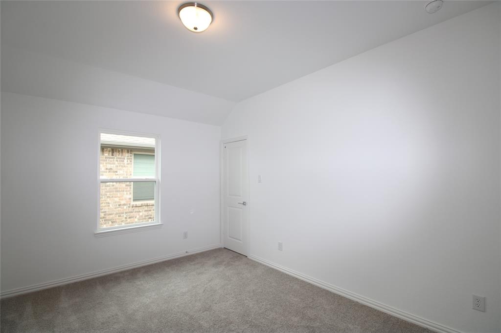 Neutral wall tones, wall-to-wall carpeting, vaulted ceiling, single-panel interior door, and flush-mount lighting