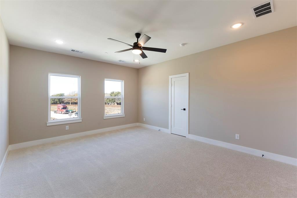 Neutral-toned interior featuring plush carpeting, dual windows, recessed lighting, and a multi-blade ceiling fan