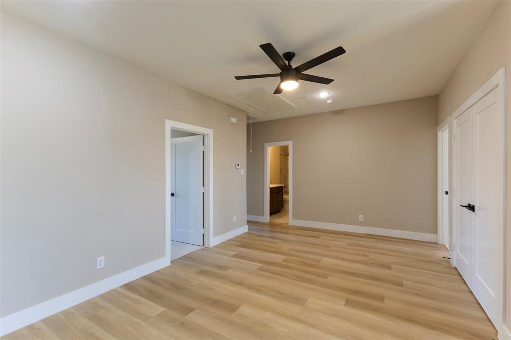 Interior space featuring wood-finish flooring, neutral wall color, matte black ceiling fan with integrated lighting, and multiple white paneled doors