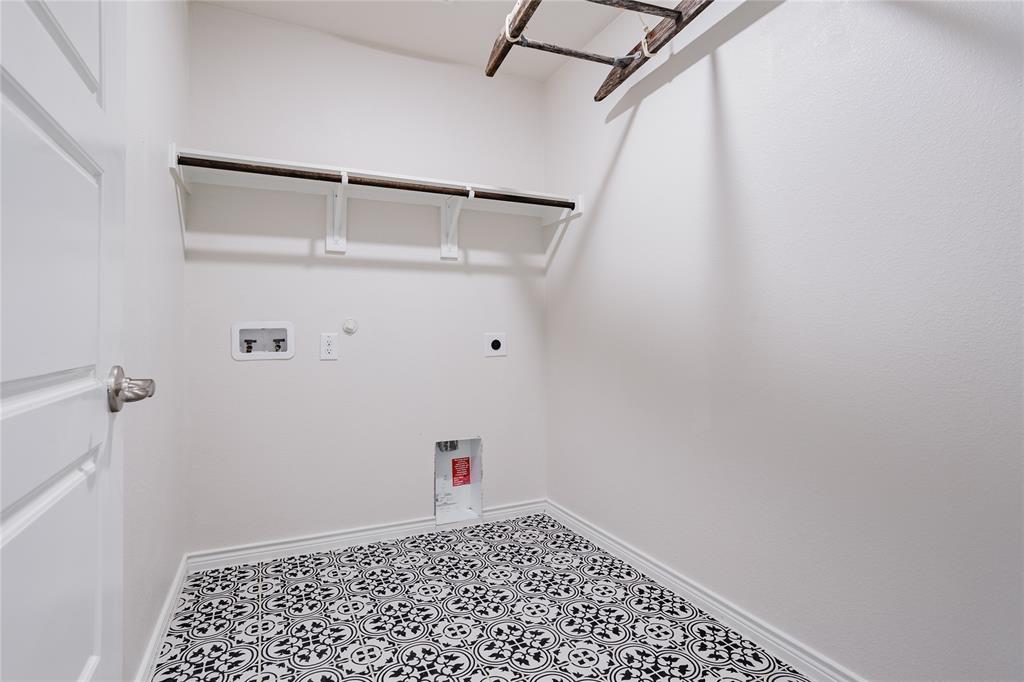 Laundry room featuring patterned tile flooring, built-in shelving, and utility hookups