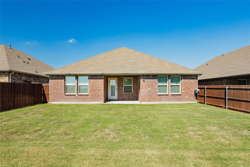 Brick exterior, hip roof, and rear lawn enclosed by wood privacy fencing