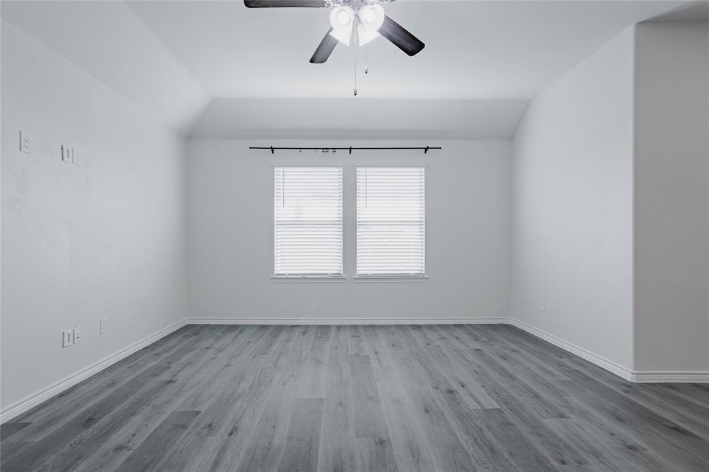 Vaulted ceiling, wood-finish flooring, dual windows with fitted blinds, and ceiling fan with integrated lighting