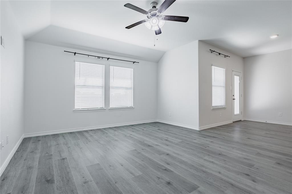 Vaulted ceilings, wood-finish flooring, multi-pane windows with horizontal blinds, and a central ceiling fan with integrated lighting