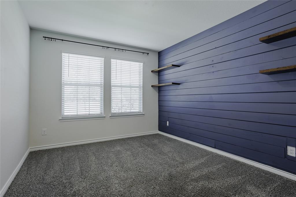 Room featuring blue horizontal shiplap accent wall, built-in floating wood-finish shelving, carpeted flooring, and dual windows with fitted blinds