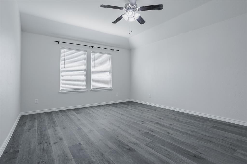 Tray ceiling featuring a central brushed-nickel finish ceiling fan with light kit, paired with wood-finish flooring and dual windows with window blinds