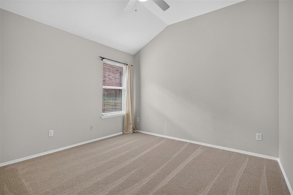 Vaulted ceiling with neutral wall tones, wall-to-wall carpeting, and a single-pane window