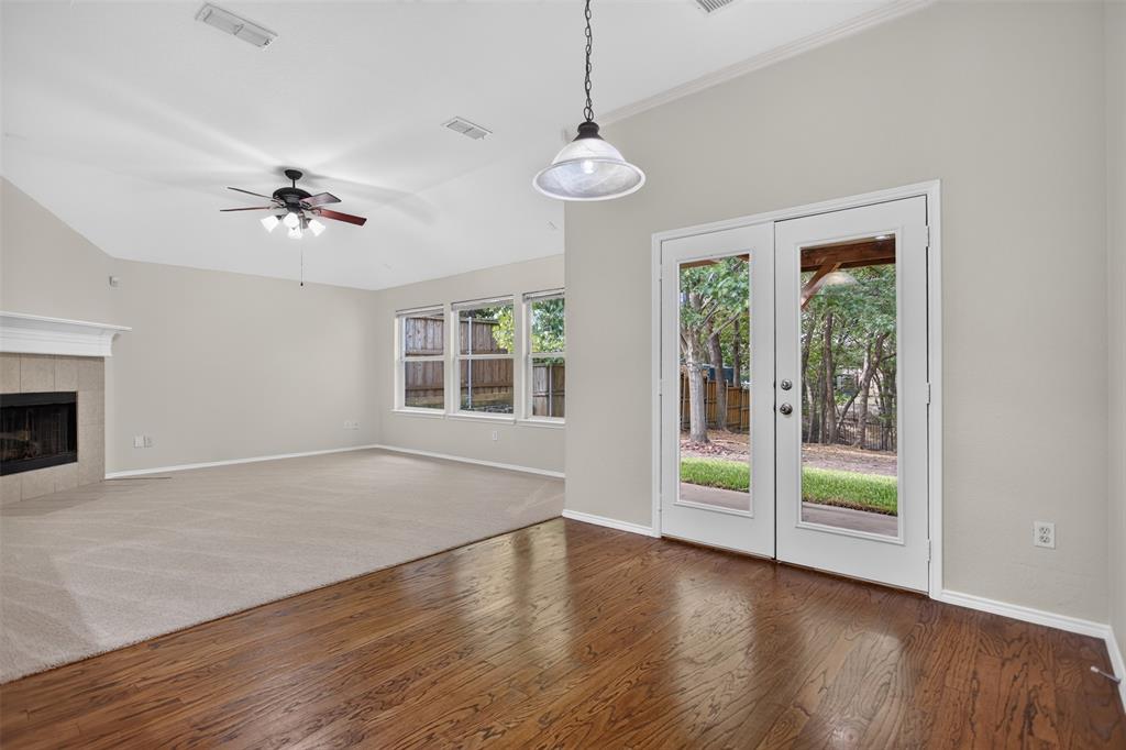 Vaulted ceilings, wood-finish flooring, fireplace with a mantel, ceiling fan, and double-glass paneled doors