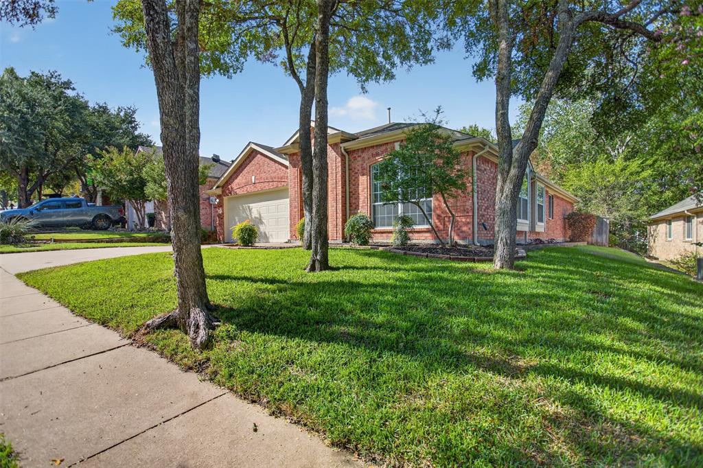 Brick exterior featuring a multi-gabled roofline, an attached two-car garage, large grid-pane windows, and a landscaped front yard with mature trees Brick exterior featuring a multi-gabled roofline, an attached two-car garage, large grid-pane windows, and a landscaped front yard with mature trees