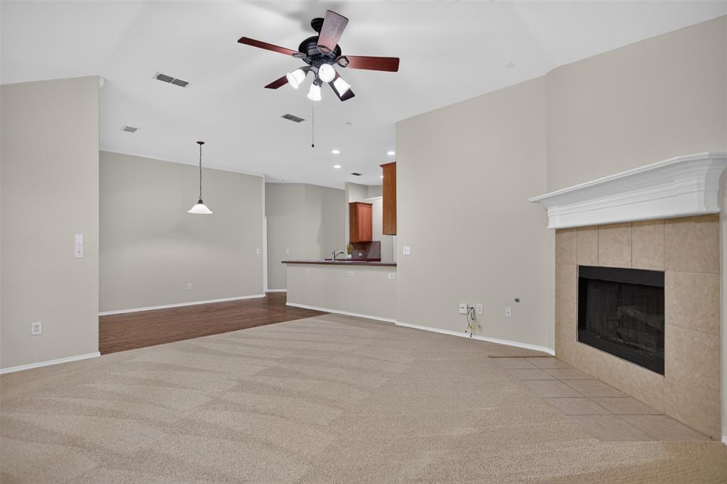Vaulted ceilings, fireplace with a decorative mantle and tile surround, ceiling fan, and pendant lighting