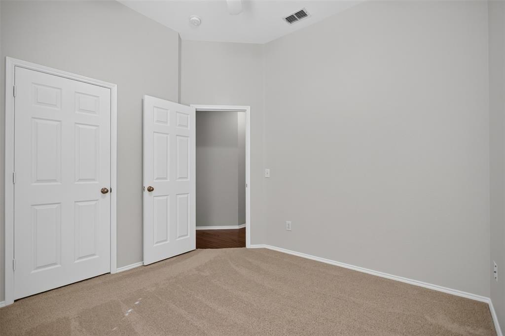 Neutral-toned room featuring plush carpeting, vaulted ceilings, and white six-panel interior doors