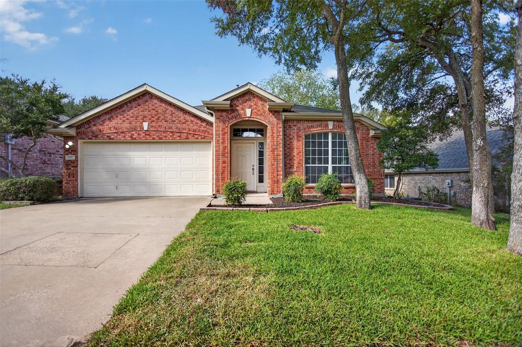 Brick exterior with a gabled roofline, an arched entryway, grid-pattern windows, and an attached two-car garage
