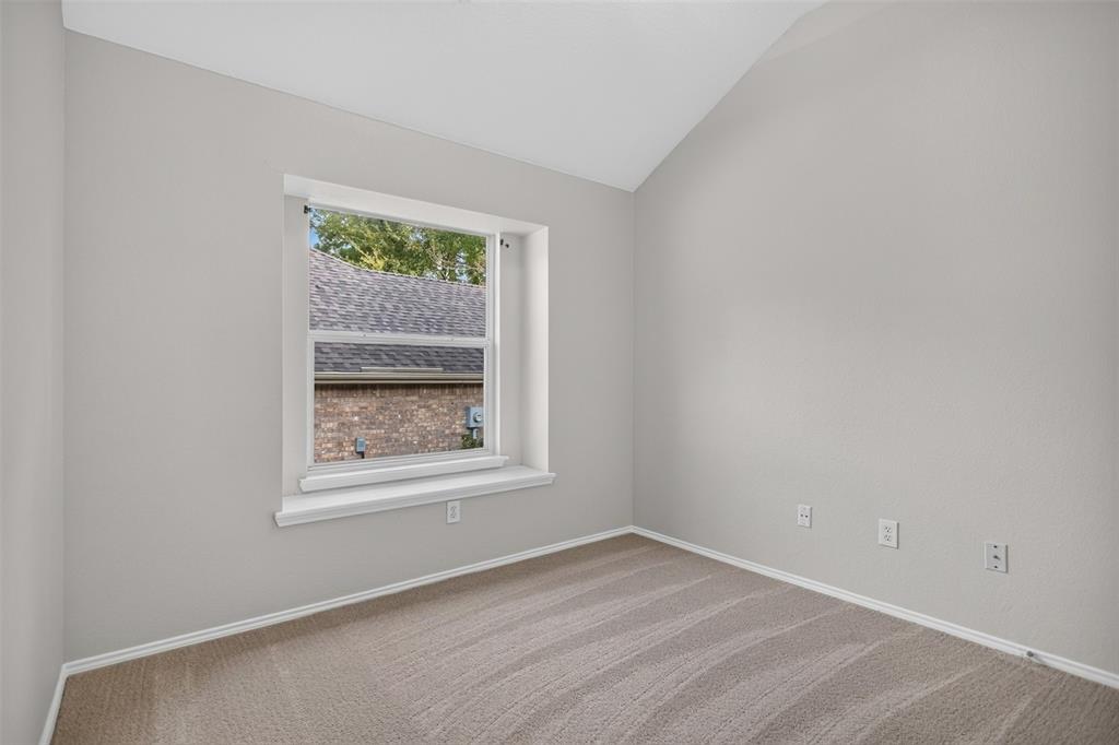 Vaulted ceiling, neutral wall tones, carpeted flooring, and a recessed window with a sill
