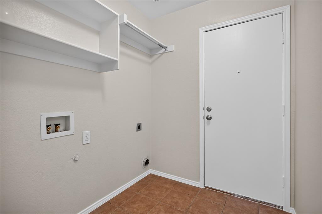 Utility space featuring ceramic tile flooring, built-in white shelving, and dedicated plumbing connections