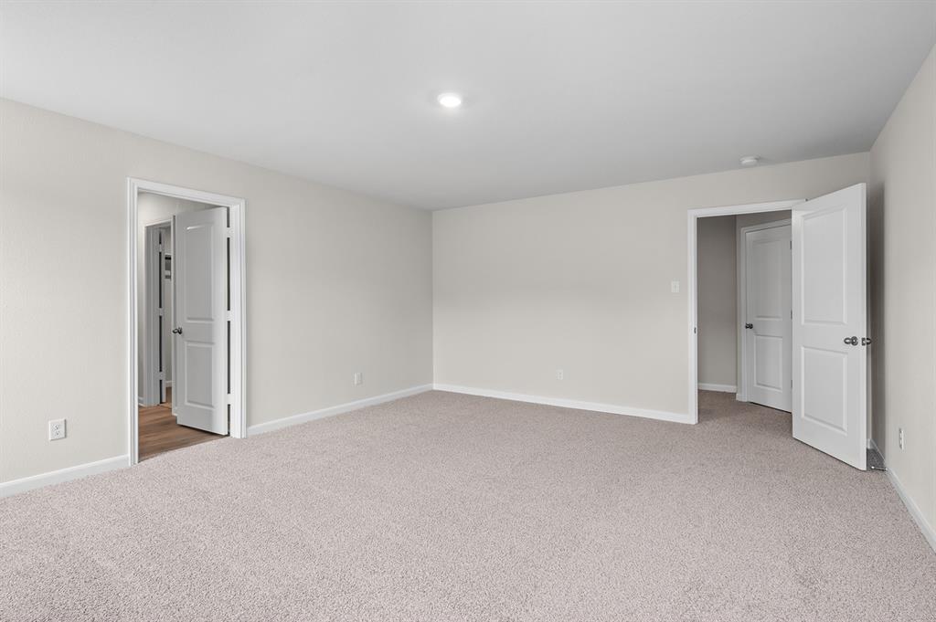 Unfurnished bedroom featuring light carpet and baseboards