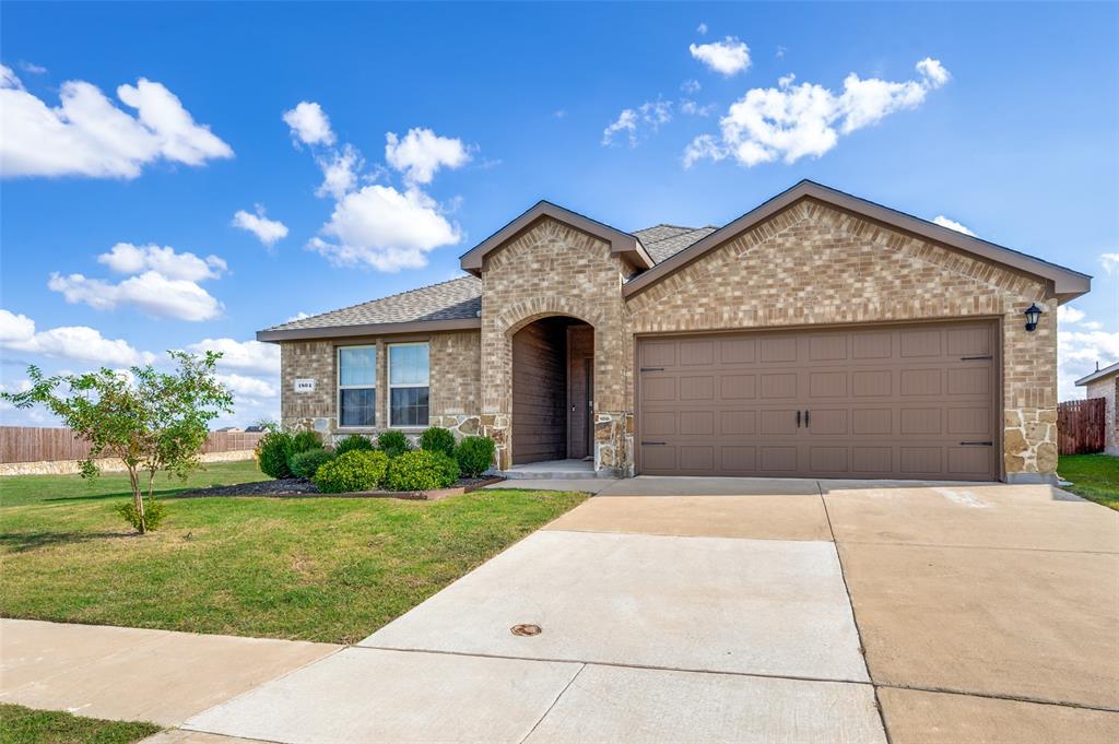 Brick and stone facade exterior featuring a covered entryway, attached two-car garage, and concrete driveway Brick and stone facade exterior featuring a covered entryway, attached two-car garage, and concrete driveway