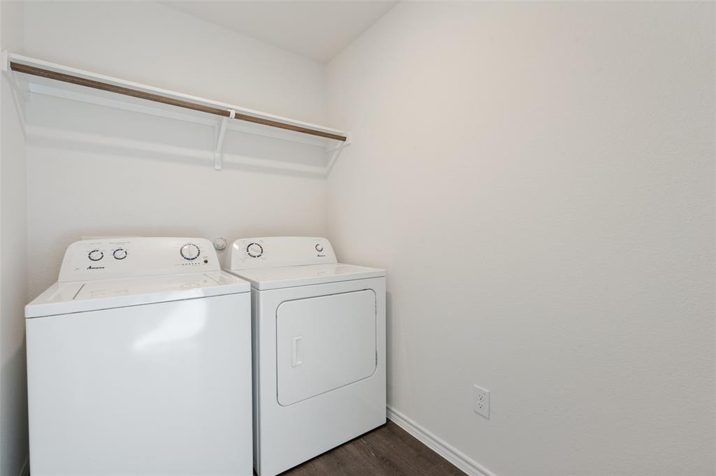 Laundry room featuring a built-in overhead shelf with hanging rod and wood-finish flooring