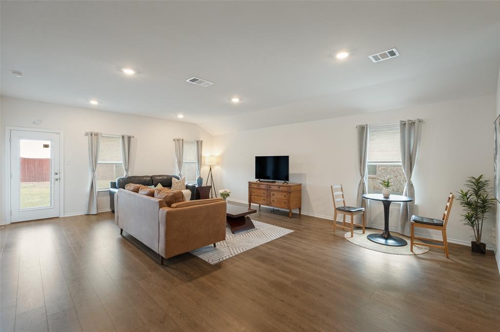 Open-concept room featuring wood-finish flooring, recessed lighting, and multiple windows with neutral window treatments