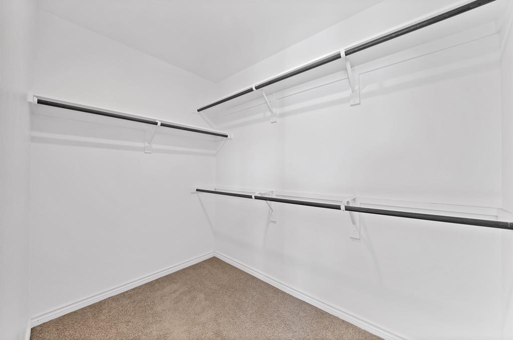 Walk-in closet featuring wall-to-wall carpeting and multi-tier metal shelving with integrated clothing rods