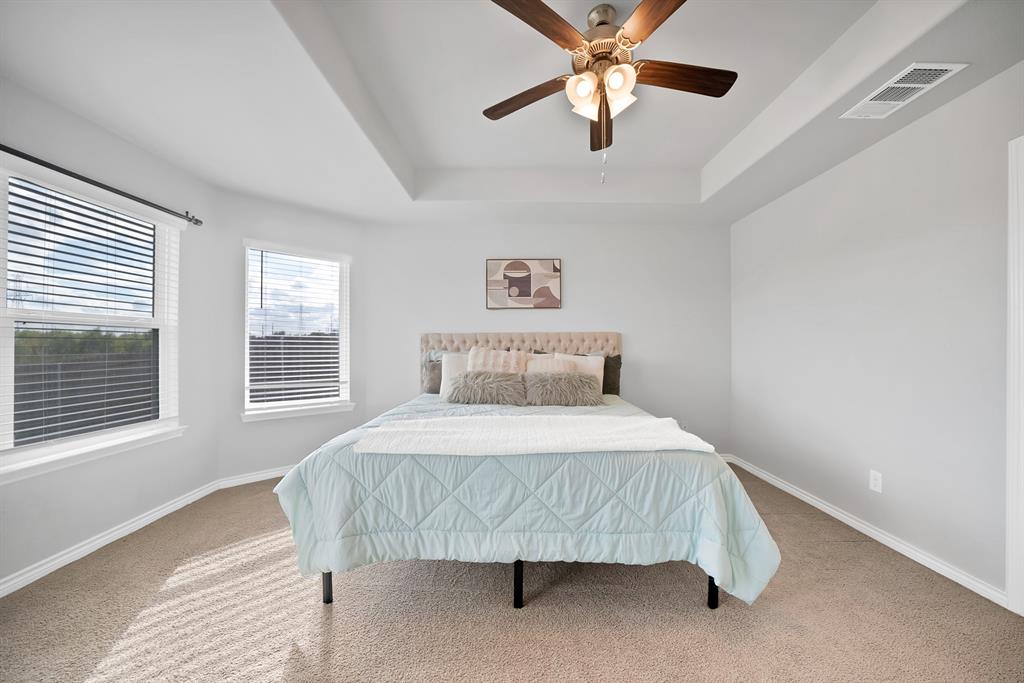 Room featuring a tray ceiling, ceiling fan with integrated lighting, and dual windows