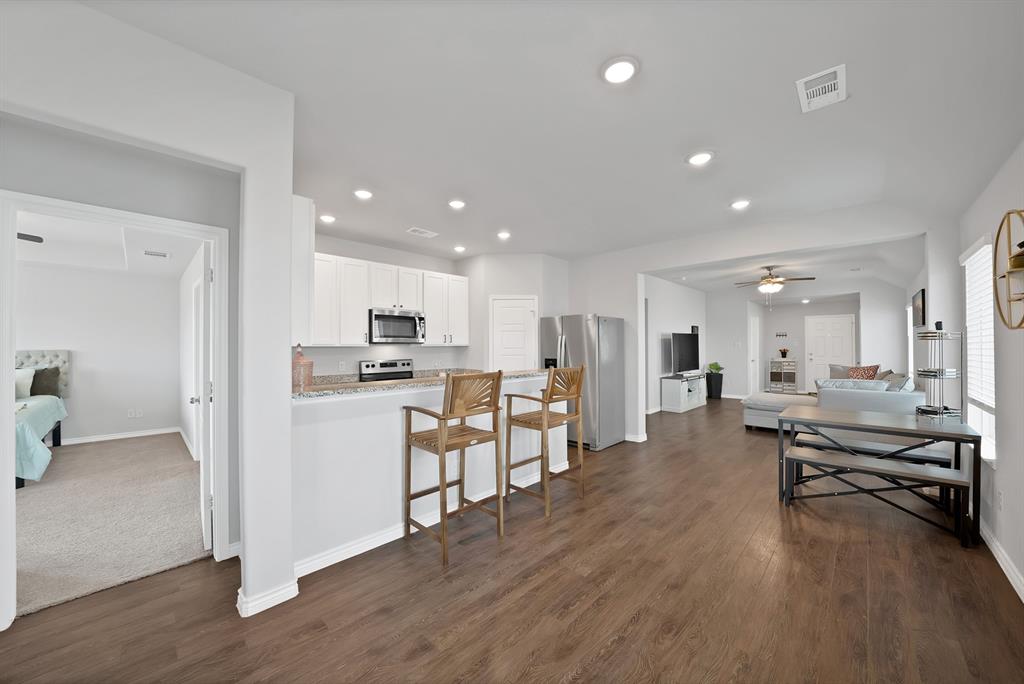 Kitchen featuring white shaker-style cabinetry, stone-finish countertops, stainless steel appliances, recessed lighting, and wood-finish flooring