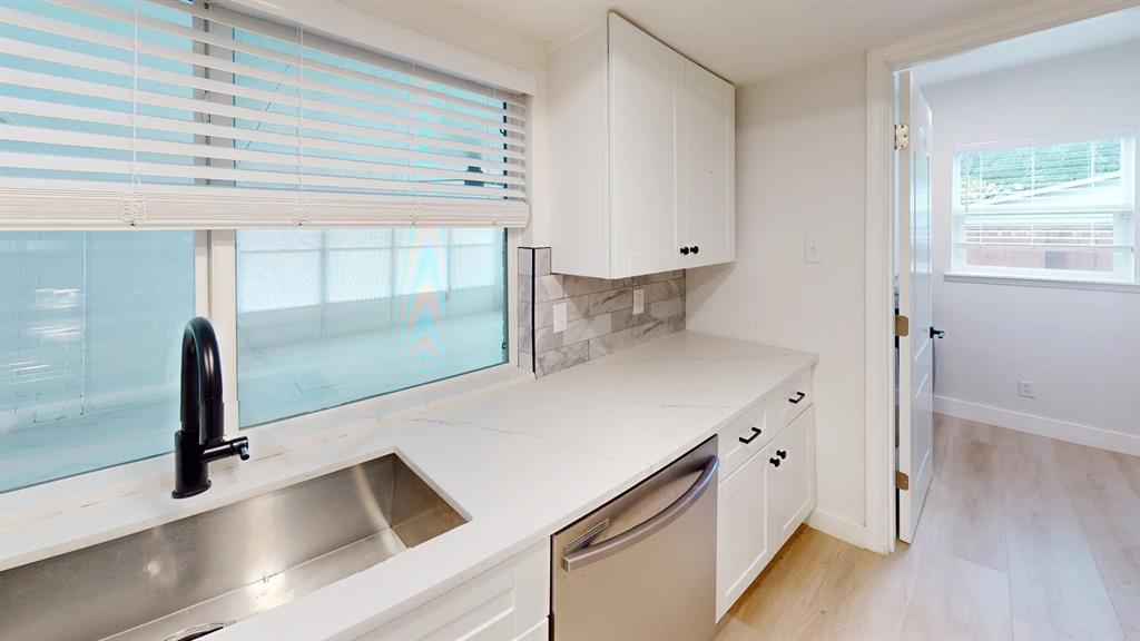 Kitchen featuring white shaker cabinetry, stone-finish countertops, stainless steel undermount sink with a matte black faucet, and patterned tile backsplash