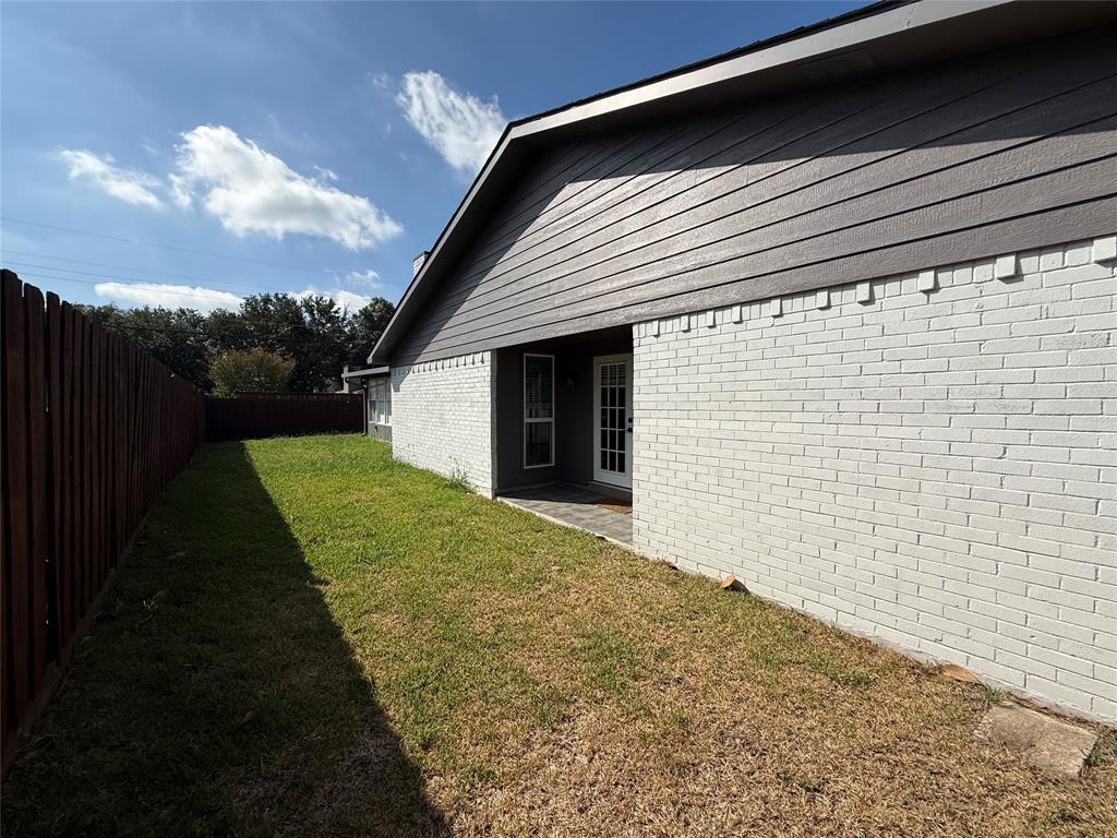 Side yard featuring white painted brick exterior, horizontal siding, and wooden privacy fencing