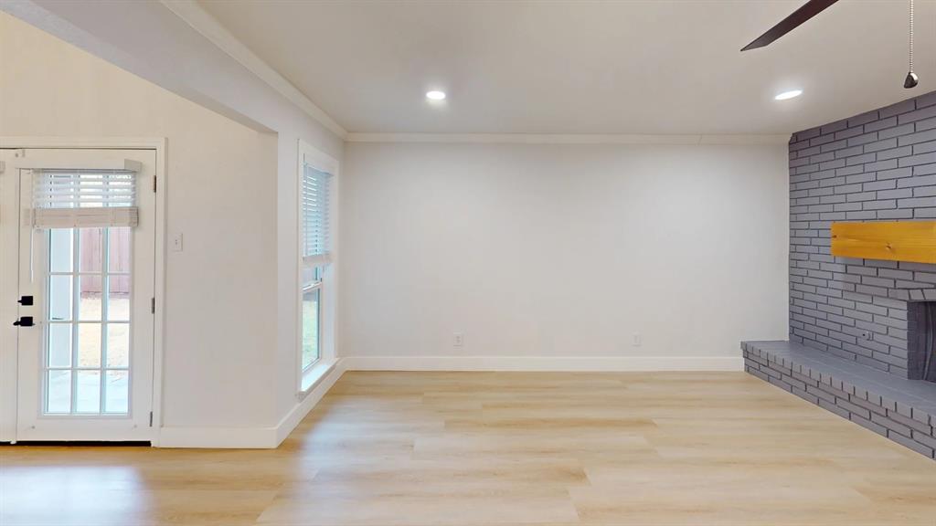 Living area featuring wood-finish flooring, a painted brick fireplace with a wood mantel, recessed lighting, and a glass-paneled exterior door
