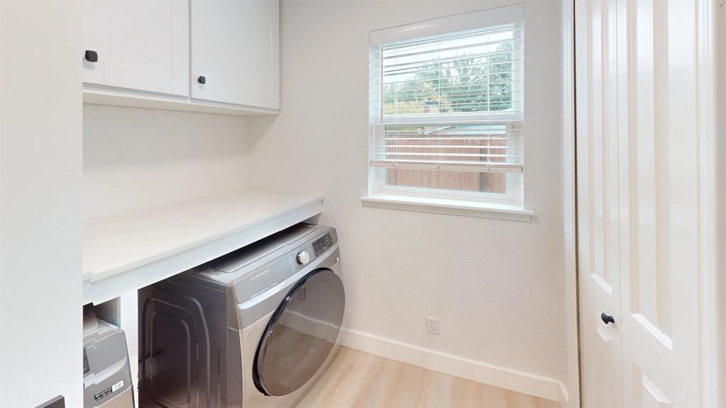 Utility room featuring white shaker-style upper cabinetry, a solid-surface folding counter, wood-finish flooring, and a louvered bi-fold closet door