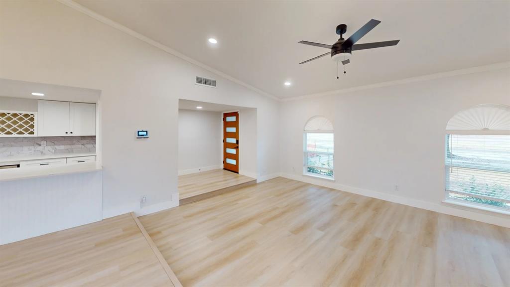 Vaulted ceilings, wood-finish flooring, recessed lighting, arched windows, and a wood-panel front door with glass inserts