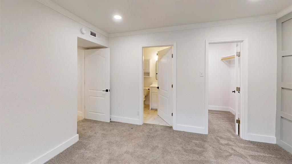 Neutral carpeted flooring, recessed lighting, crown molding, paneled wall accent, and multiple interior doors with matte black hardware