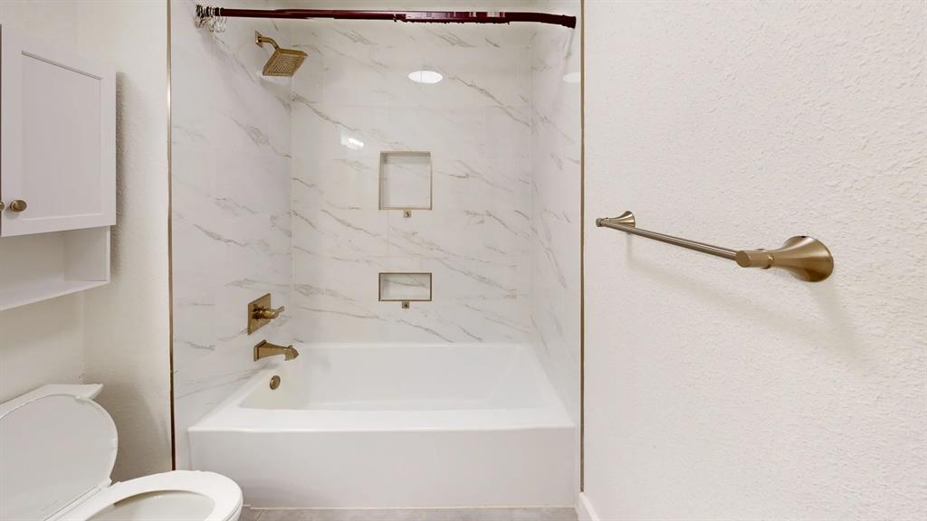 Bathtub and shower combination featuring stone-finish wall surround, dual built-in recessed niches, and metallic-finish hardware Bathtub and shower combination featuring stone-finish wall surround, dual built-in recessed niches, and metallic-finish hardware