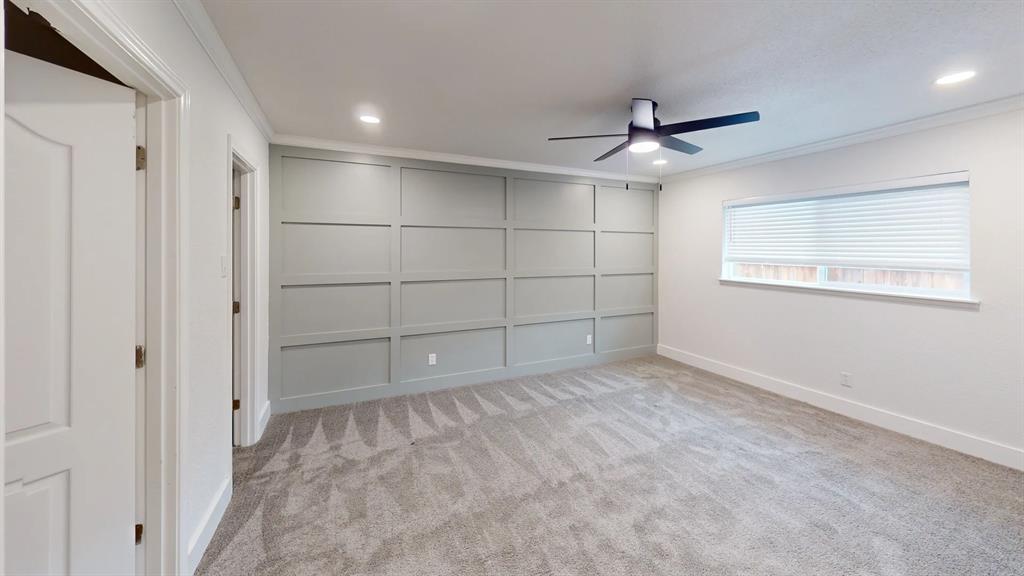 Grey-painted wainscoting accent wall, recessed lighting, ceiling fan with integrated lighting, neutral wall-to-wall carpeting, and horizontal window blinds