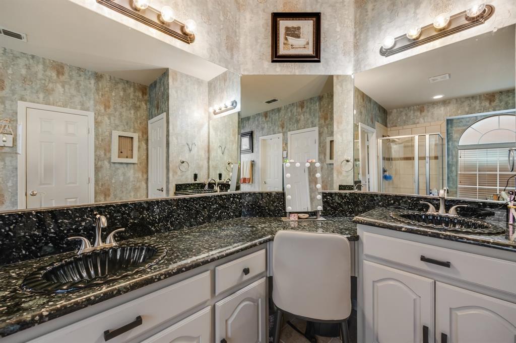 Bathroom featuring a stall shower, two vanities, and wallpapered walls