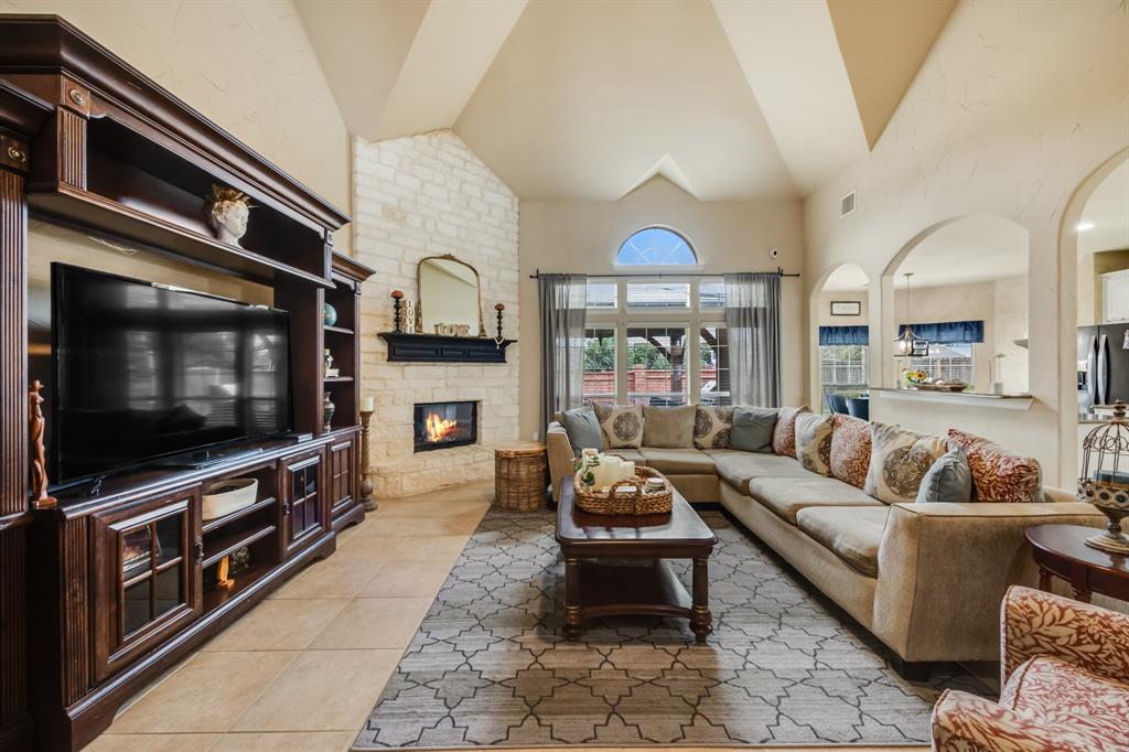 Living area with light tile patterned floors, high vaulted ceiling, and a large fireplace