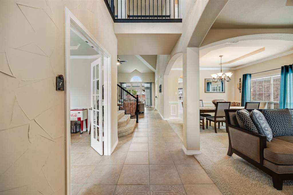 Entryway featuring arched walkways, tile patterned floors, stairway, a chandelier, and carpet flooring