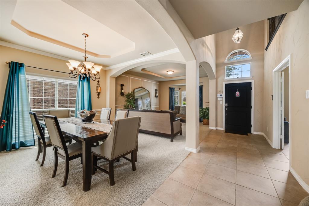 Dining area with a chandelier, light tile patterned floors, light colored carpet, and a tray ceiling