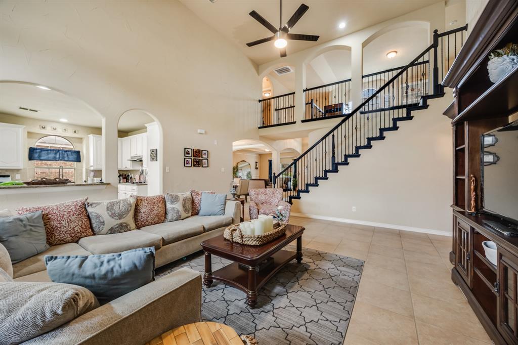 Living area with stairs, arched walkways, recessed lighting, a high ceiling, and light tile patterned floors