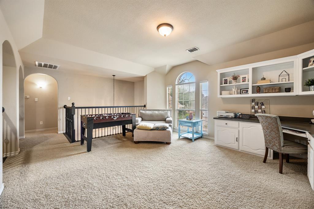Office with light colored carpet, arched walkways, built in desk, a textured ceiling, and vaulted ceiling