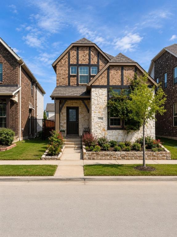 Tudor-style exterior featuring stone veneer, half-timbered gables, a covered entry, and custom raised stone garden beds