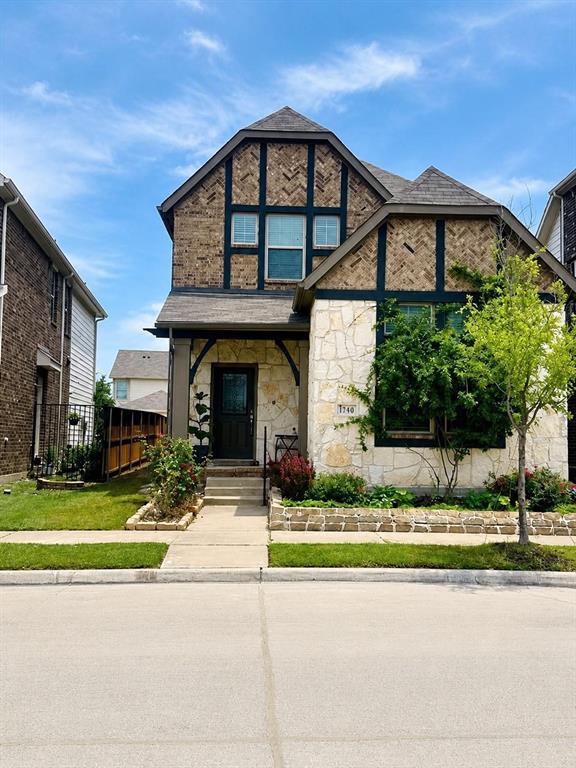 Tudor-style exterior featuring stone cladding, decorative timber framing, herringbone brickwork accents, and a covered front entry