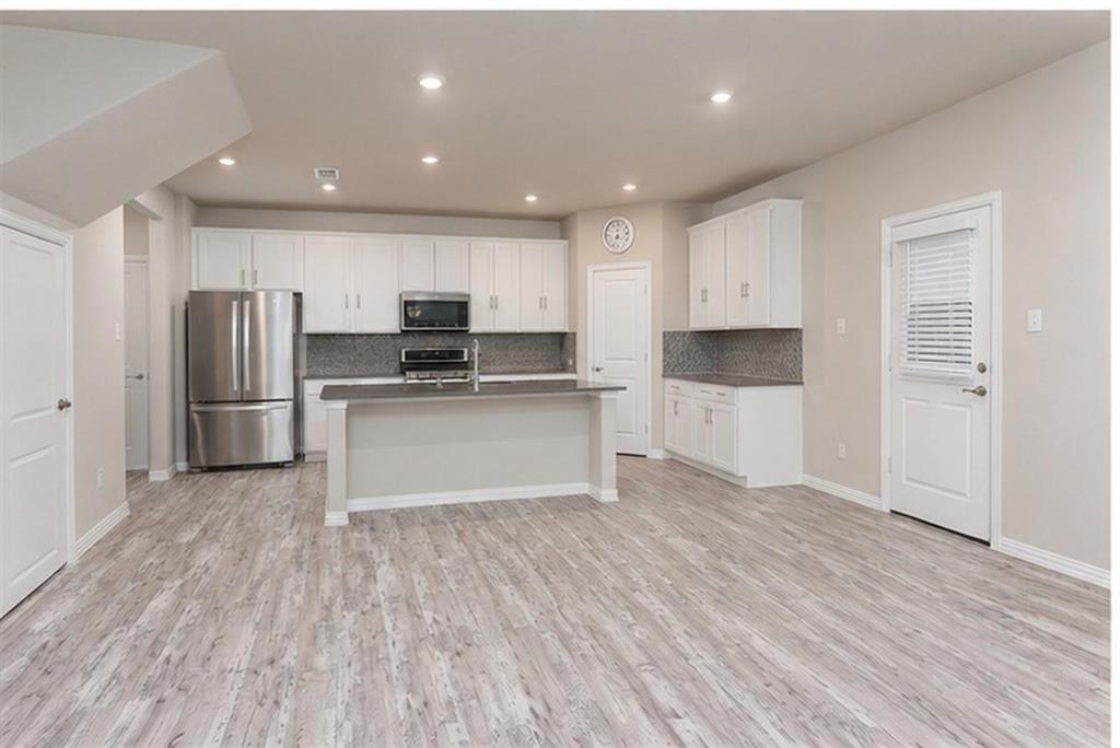 Kitchen featuring white cabinetry, an island with stone-finish countertops, recessed lighting, and wood-finish flooring