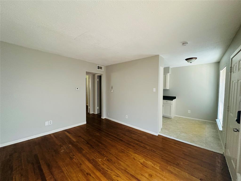 Interior featuring wood-finish flooring, neutral wall paint, and white kitchen cabinetry with dark countertops