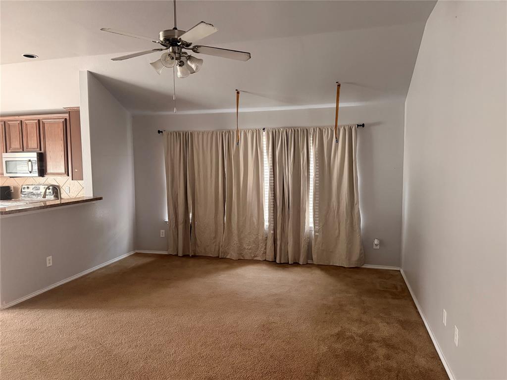 Vaulted ceiling, carpeted flooring, brushed nickel ceiling fan with integrated lighting, and pass-through counter overlooking the kitchen area Vaulted ceiling, carpeted flooring, brushed nickel ceiling fan with integrated lighting, and pass-through counter overlooking the kitchen area