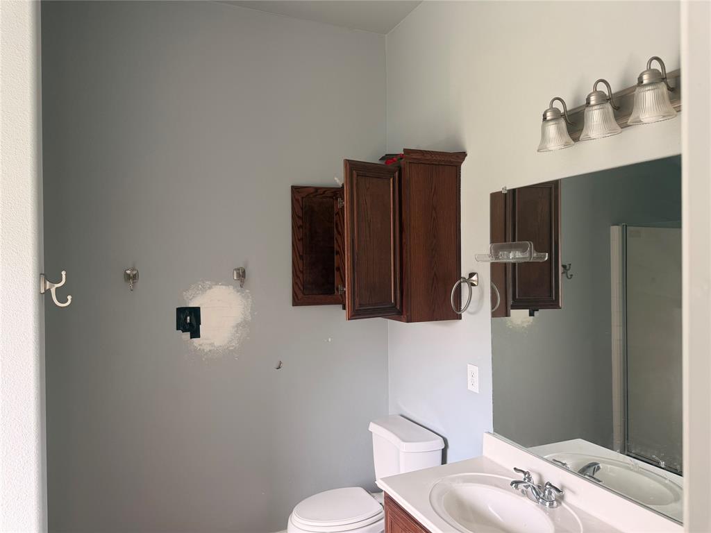 Vanity featuring a white surface, undermount basin, and wood-finish cabinetry, complemented by a large wall-mounted mirror, three-light fixture, and dark wood wall-mounted cabinet