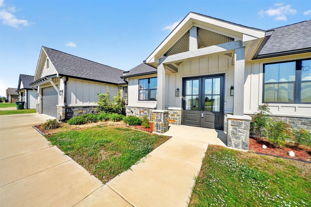 Board-and-batten siding exterior featuring stone veneer accents, a covered front entryway with timber-style posts, and double front entry doors Board-and-batten siding exterior featuring stone veneer accents, a covered front entryway with timber-style posts, and double front entry doors