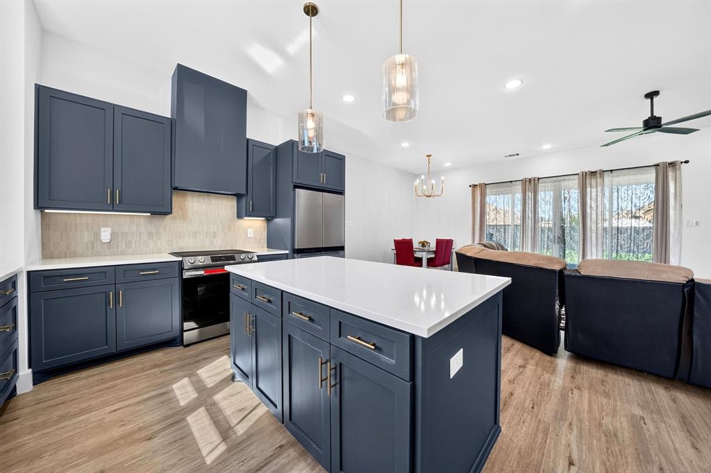 Kitchen featuring shaker-style navy cabinetry, stone-surface countertops, a center island, wood-finish flooring, and glass pendant lighting