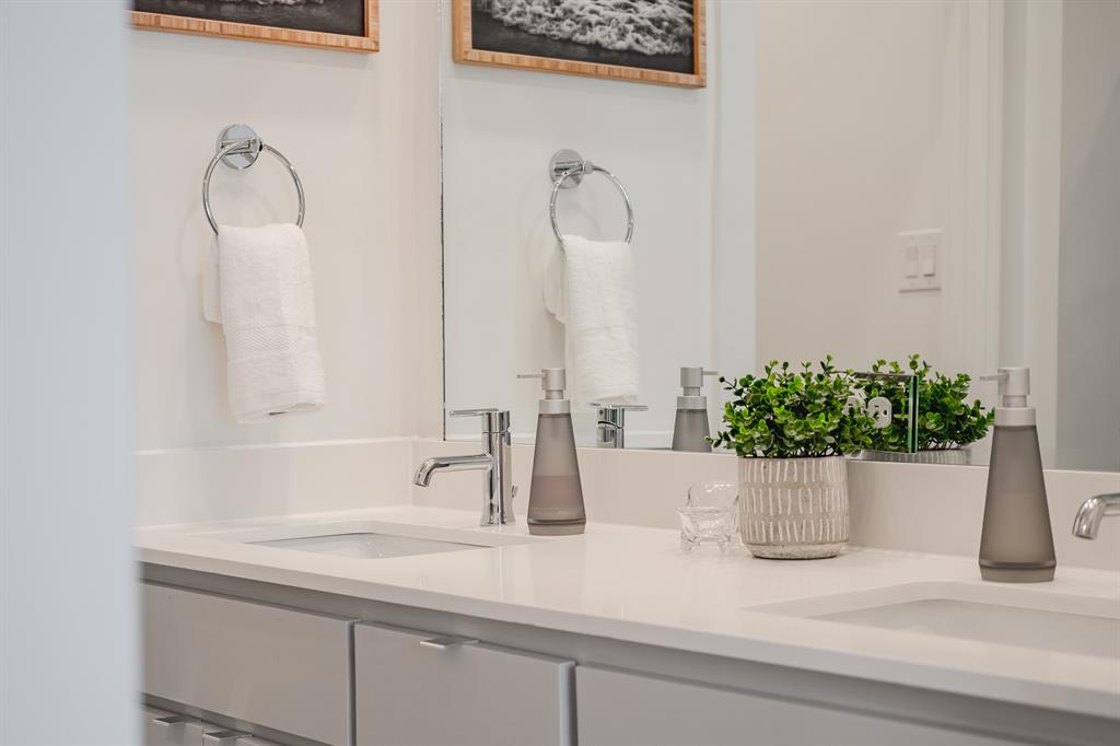 Double vanity featuring white solid-surface countertops, dual undermount sinks, chrome fixtures, and grey cabinetry