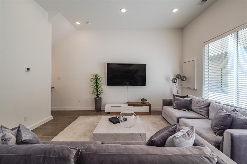 Living area featuring vaulted ceilings, recessed lighting, wood-finish flooring, and large windows with horizontal blinds